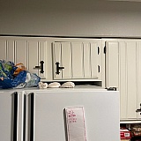 Broken cabinet door in kitchen about the refrigerator