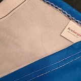 Printerpix blanket showing messy-looking stitching, carelessly hemmed so white shows on top, white stitching on dark colors, and corner edges bunched up.